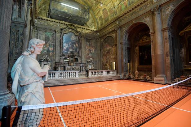 Ein Tennisplatz befindet sich in einem reich verzierten Raum mit Gemälden und einer Statue.