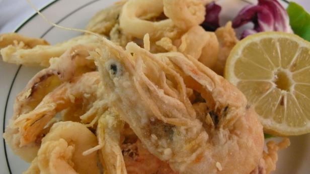 Ein Teller mit frittierten Meeresfrüchten und einer Zitronenscheibe.
