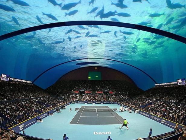 Ein Tennisspiel in Basel unter einem Aquarium mit vielen Fischen.