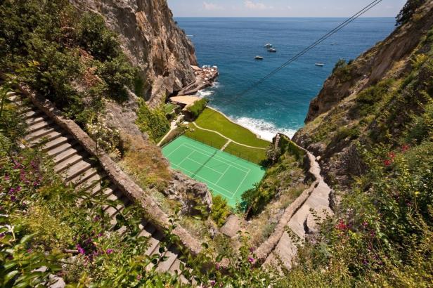 Ein Tennisplatz liegt malerisch zwischen Klippen am Meer.