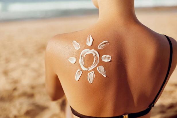Sonnencreme in Form einer Sonne auf dem Rücken einer Frau am Strand.