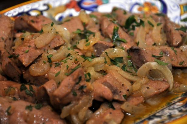 Gebratene Leber mit Zwiebeln und Petersilie auf einem Teller.