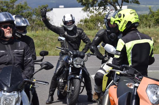 Eine Gruppe von Motorradfahrern macht eine Pause auf der Straße.