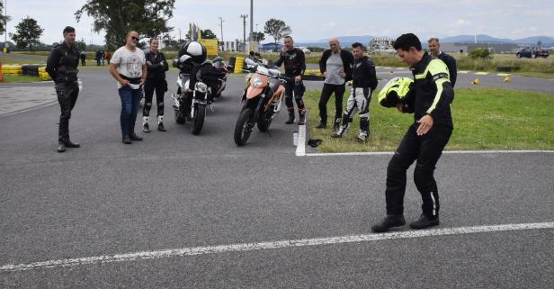 Eine Gruppe von Motorradfahrern steht auf einer asphaltierten Strecke.