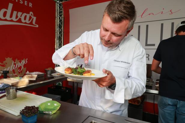 Christof Widakovich garniert ein Gericht mit Jakobsmuscheln und Salat.