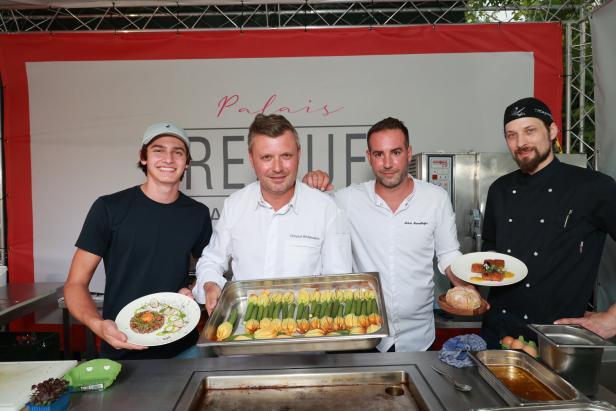 Vier Köche präsentieren Gerichte und gefüllte Zucchiniblüten vor dem Palais Freue..