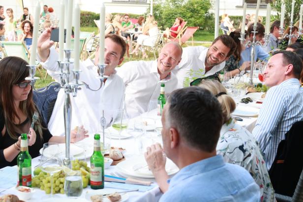 Eine Gruppe von Menschen sitzt an einem Tisch im Freien und genießt ein Essen.
