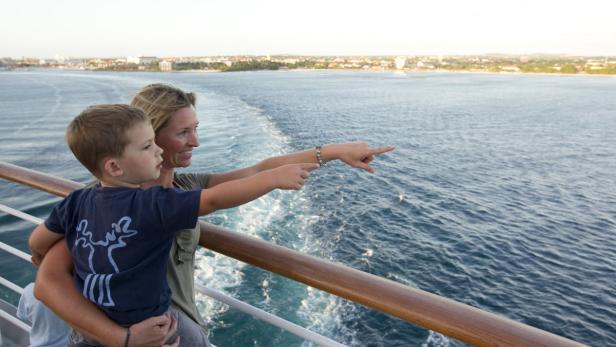Eine Mutter mit ihrem Sohn auf einem Schiff, beide zeigen auf das Meer.