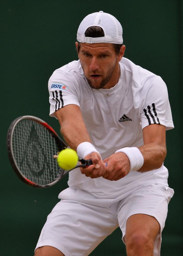 Ein Tennisspieler schlägt einen gelben Tennisball mit seinem Schläger.