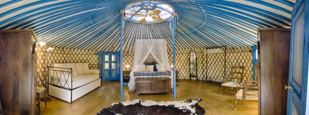 Innenansicht einer Jurte mit Himmelbett und traditionellen Möbeln.