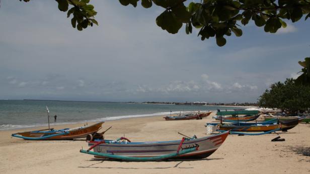 Mehrere bunte Fischerboote liegen am Strand.