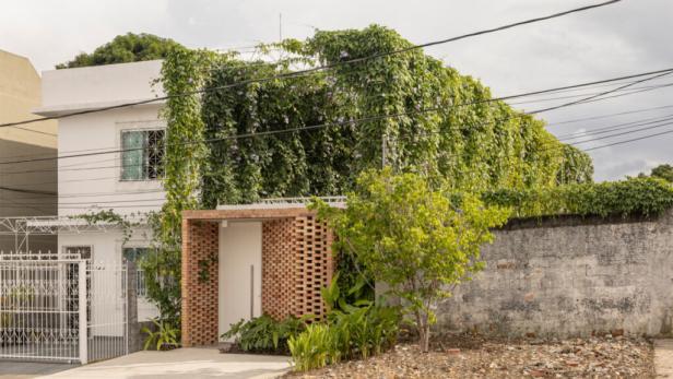 Ein weißes Haus, teilweise mit üppiger grüner Vegetation bedeckt.