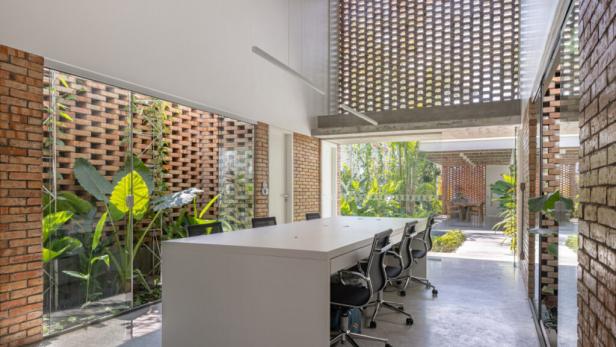 Ein Besprechungsraum mit einem großen Tisch und Blick auf einen tropischen Garten.