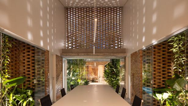 Ein langer Tisch in einem Raum mit Ziegelwänden und tropischen Pflanzen.