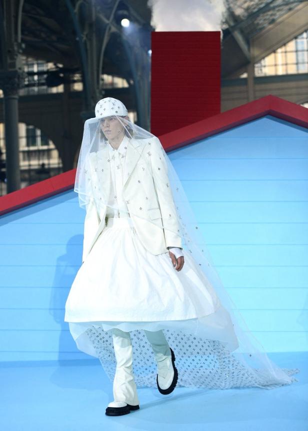 Ein Model in einem weißen Louis Vuitton-Outfit mit Schleier auf einem Laufsteg.
