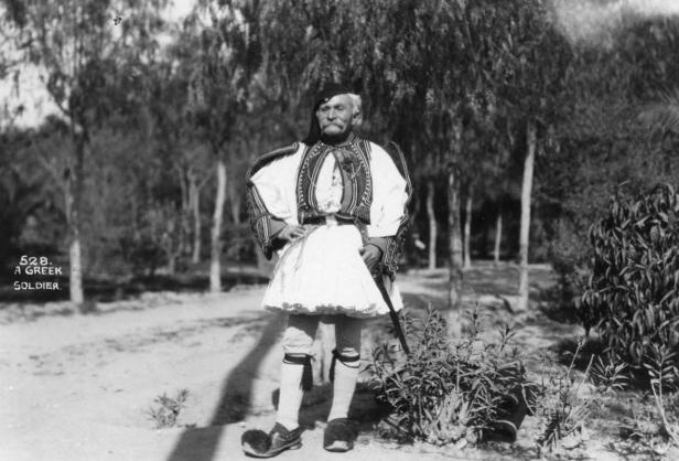 Ein älterer griechischer Soldat in traditioneller Uniform steht im Freien.