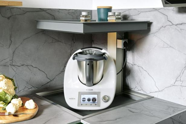 Ein Thermomix steht auf einer Küchenarbeitsplatte neben einem Blumenkohl.