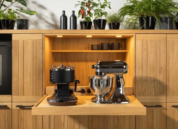 Eine Kaffeemaschine und eine Küchenmaschine stehen auf einer ausziehbaren Ablage in einer Küche.