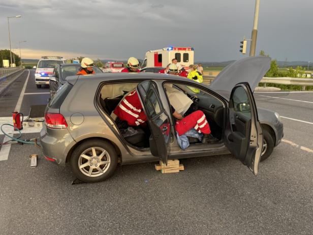 Nach einem Unfall wird eine Person in einem Auto von Rettungskräften versorgt.