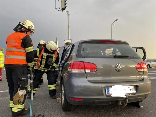 Feuerwehrleute bergen eine Person aus einem grauen VW Golf nach einem Unfall.