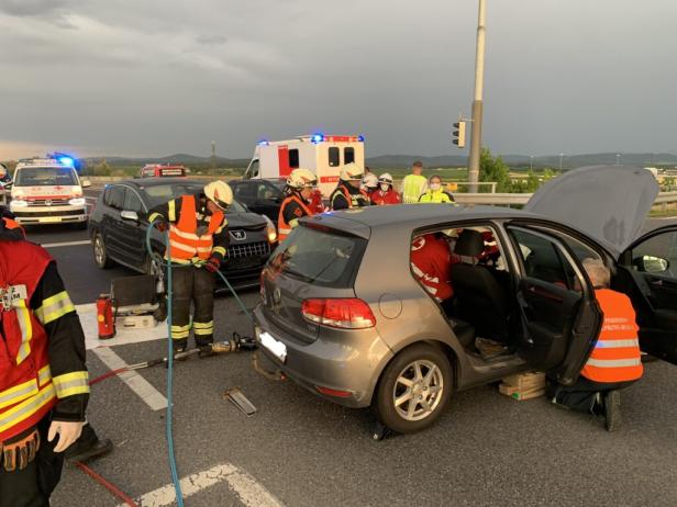 Nach einem Autounfall arbeiten Rettungskräfte an den beschädigten Fahrzeugen.
