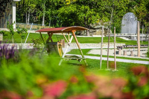 Eine überdachte Schaukel steht in einem grünen Park.