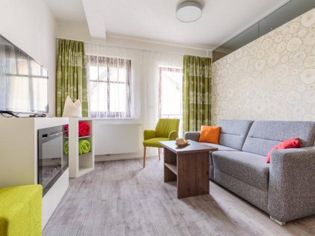 Ein Wohnzimmer mit einem grauen Sofa, einem grünen Sessel und einem Fernseher.