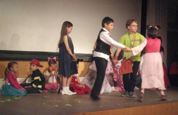 Kinder in Kostümen treten auf einer Bühne auf.