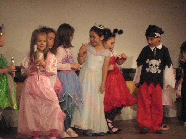 Eine Gruppe von Kindern in Kostümen steht auf einer Bühne.