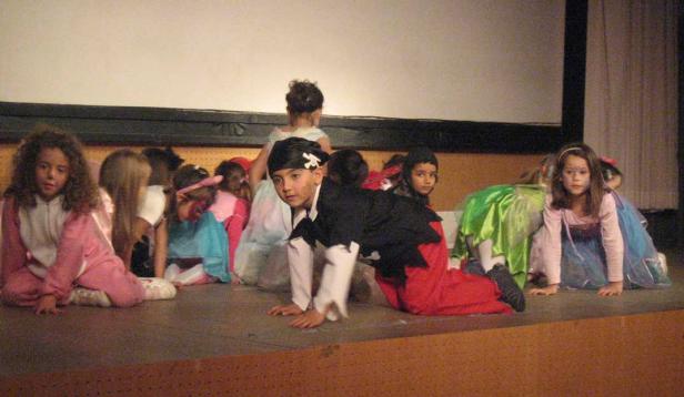 Eine Gruppe von Kindern in Kostümen kniet auf einer Bühne.