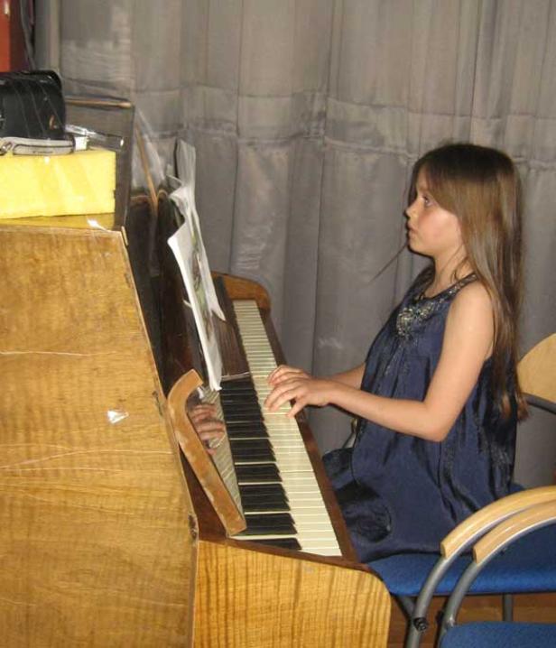 Ein junges Mädchen spielt auf einem alten Klavier.