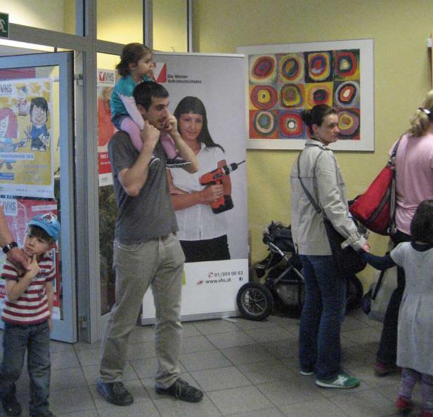 Ein Mann trägt ein kleines Mädchen auf seinen Schultern in einem VHS-Gebäude.