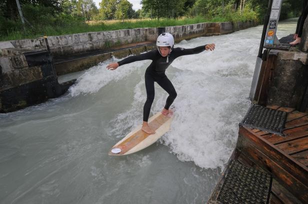 Eine Person surft auf einer stehenden Welle in einem künstlichen Kanal.