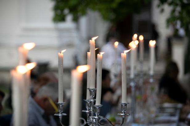 Mehrere brennende Kerzen in silbernen Kerzenständern stehen auf einem Tisch.