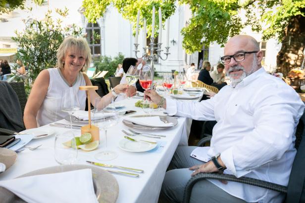 Ein Mann und eine Frau stoßen im Freien mit ihren Getränken an.