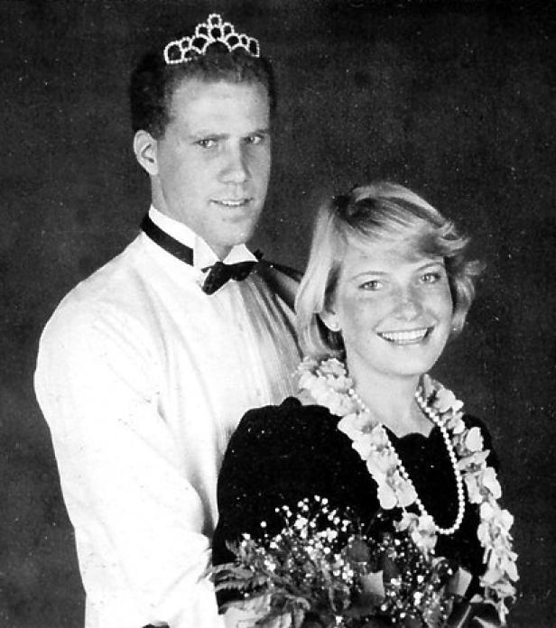 Ein Mann mit Tiara und eine Frau mit Blumenkette lächeln in die Kamera.