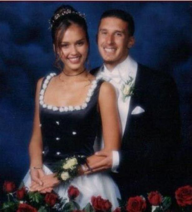 Jessica Alba und ein Mann in formeller Kleidung posieren vor einem Hintergrund mit Rosen.