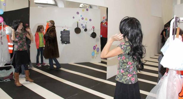 Besucher in einer Ausstellung mit Kleidern und Installationen.