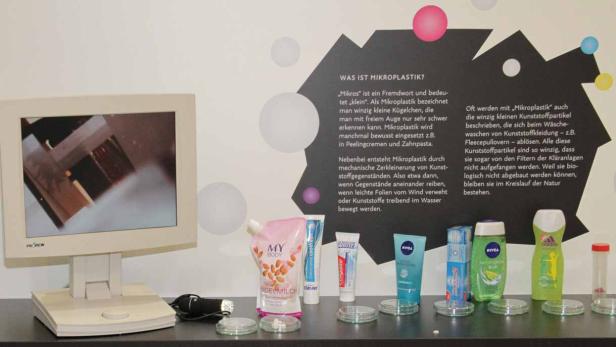 Ein Ausstellungsstück zum Thema Mikroplastik mit einem Monitor und verschiedenen Kosmetikprodukten.