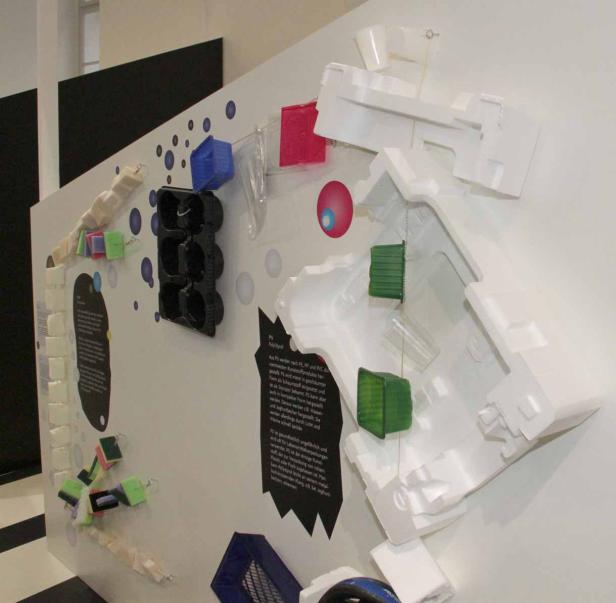 Eine Ausstellungstafel zeigt verschiedene Produkte aus Polystyrol (PS).