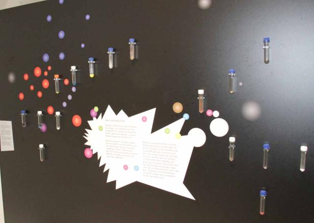 Eine Wand mit Reagenzgläsern und Erklärungen zum Thema Additive.