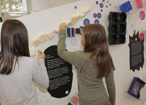 Zwei Mädchen interagieren mit einer Ausstellung über Polyurethan (PUR).