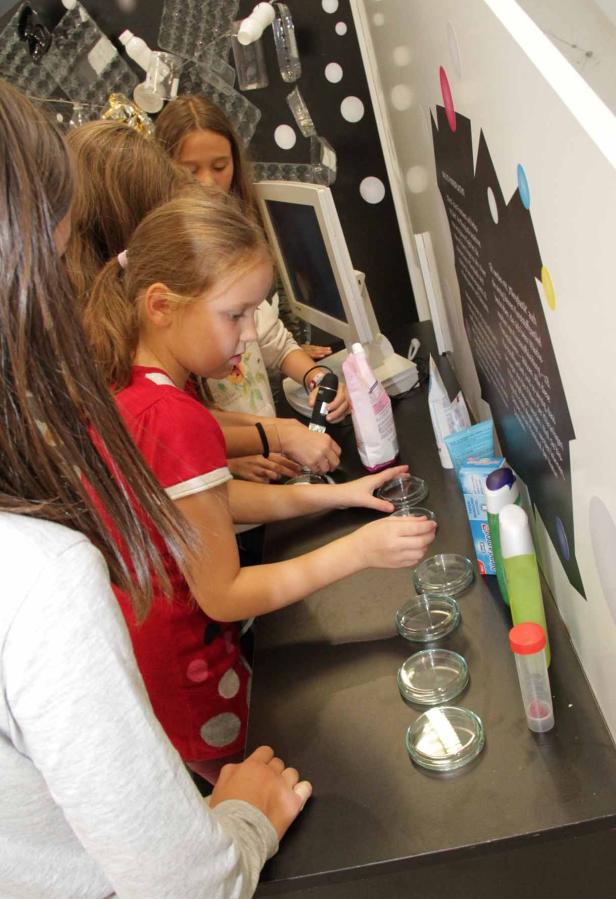 Einige Mädchen experimentieren mit Petrischalen an einem Tisch.