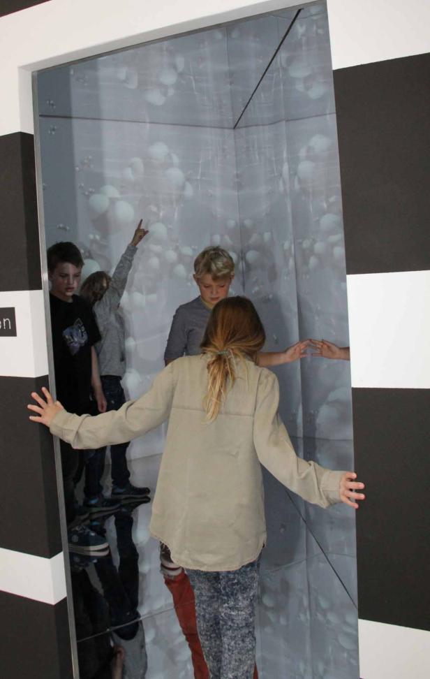 Eine Gruppe von Kindern steht in einem Raum mit einer Projektion von Blasen.