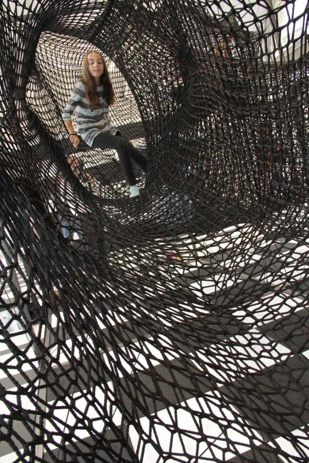 Ein Mädchen sitzt in einem großen, schwarzen Netz.