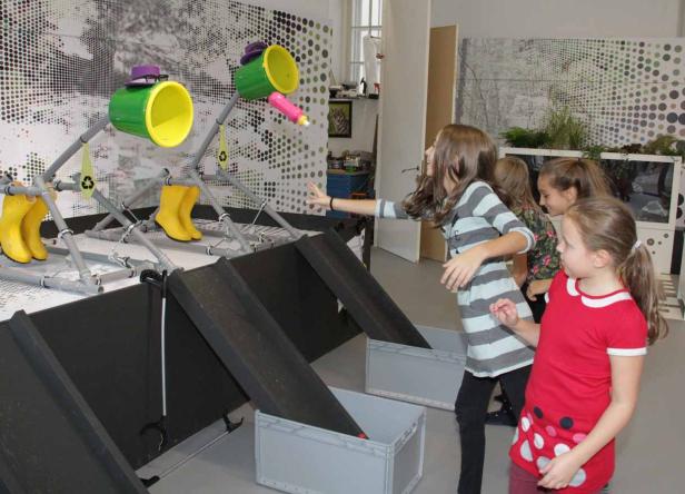 Kinder spielen ein Spiel, bei dem sie Gegenstände in Behälter werfen müssen.