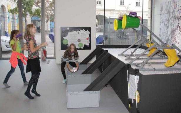 Drei Mädchen spielen mit einer Installation zum Thema Plastikmüll und Recycling.