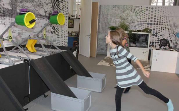 Ein Mädchen wirft einen Gegenstand in eine interaktive Recycling-Installation.