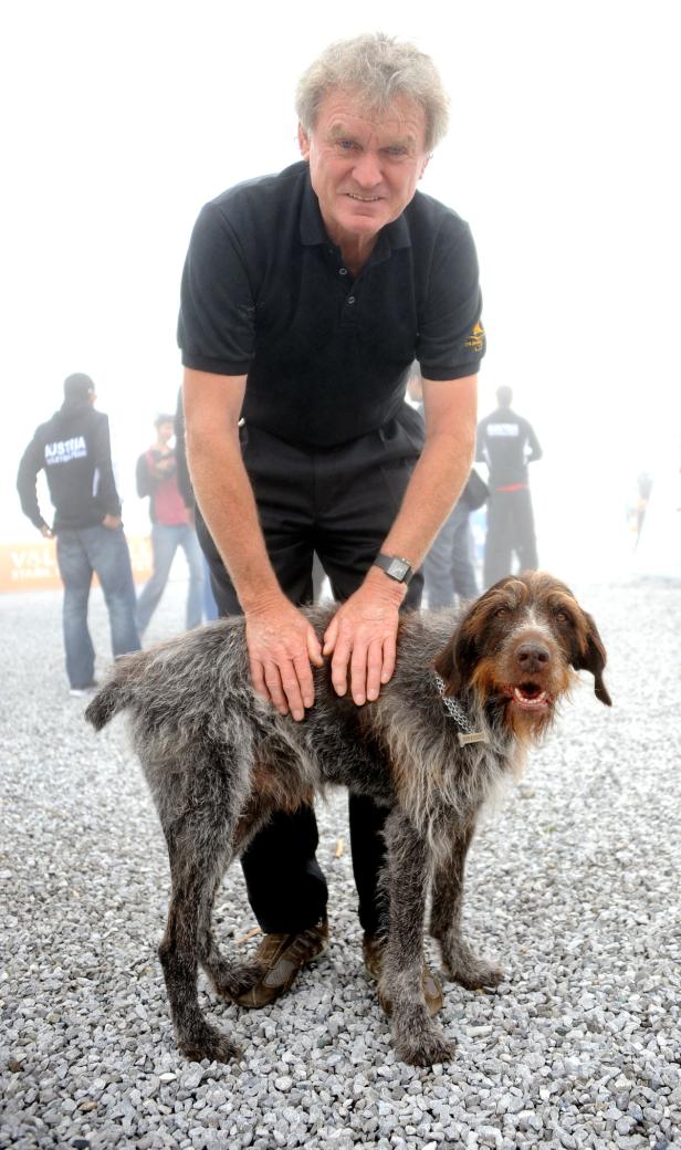 Ein Mann streichelt einen Deutsch Drahthaar Hund im Freien.
