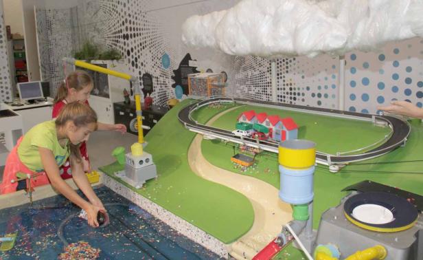 Zwei Mädchen spielen mit einem interaktiven Modell einer Stadt und einem Wassersystem.